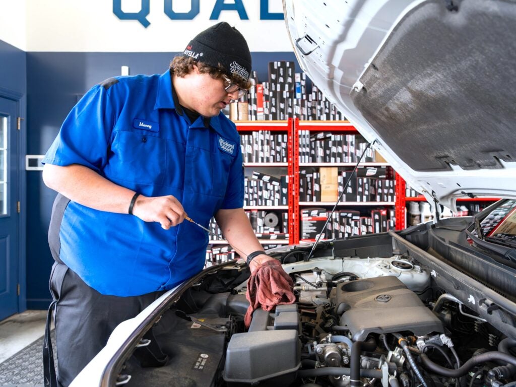 man looking in hood of car