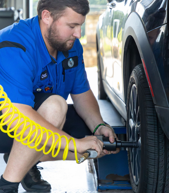 A Strickland Brothers team member helps perform a tire rotation on a vehicle at a shop.